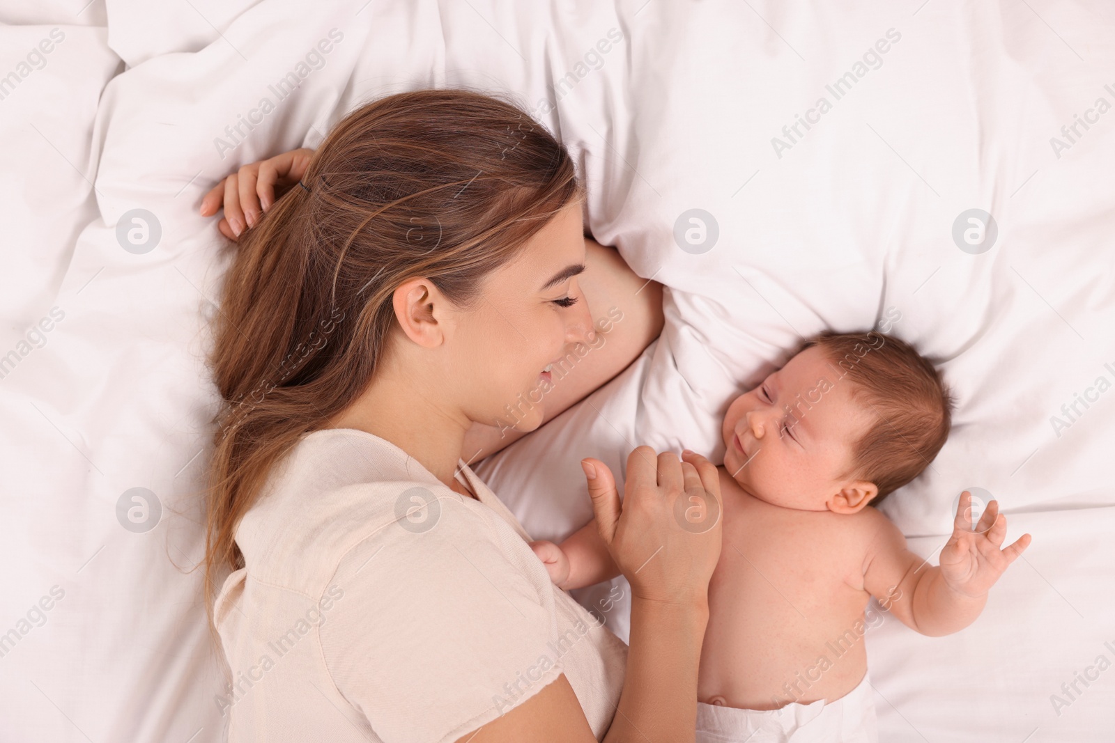 Photo of Mother and her cute newborn baby on bed, top view
