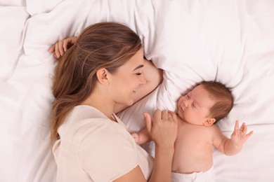 Mother and her cute newborn baby on bed, top view