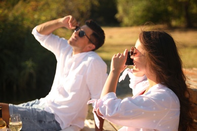 Woman taking picture of boyfriend outdoors at picnic