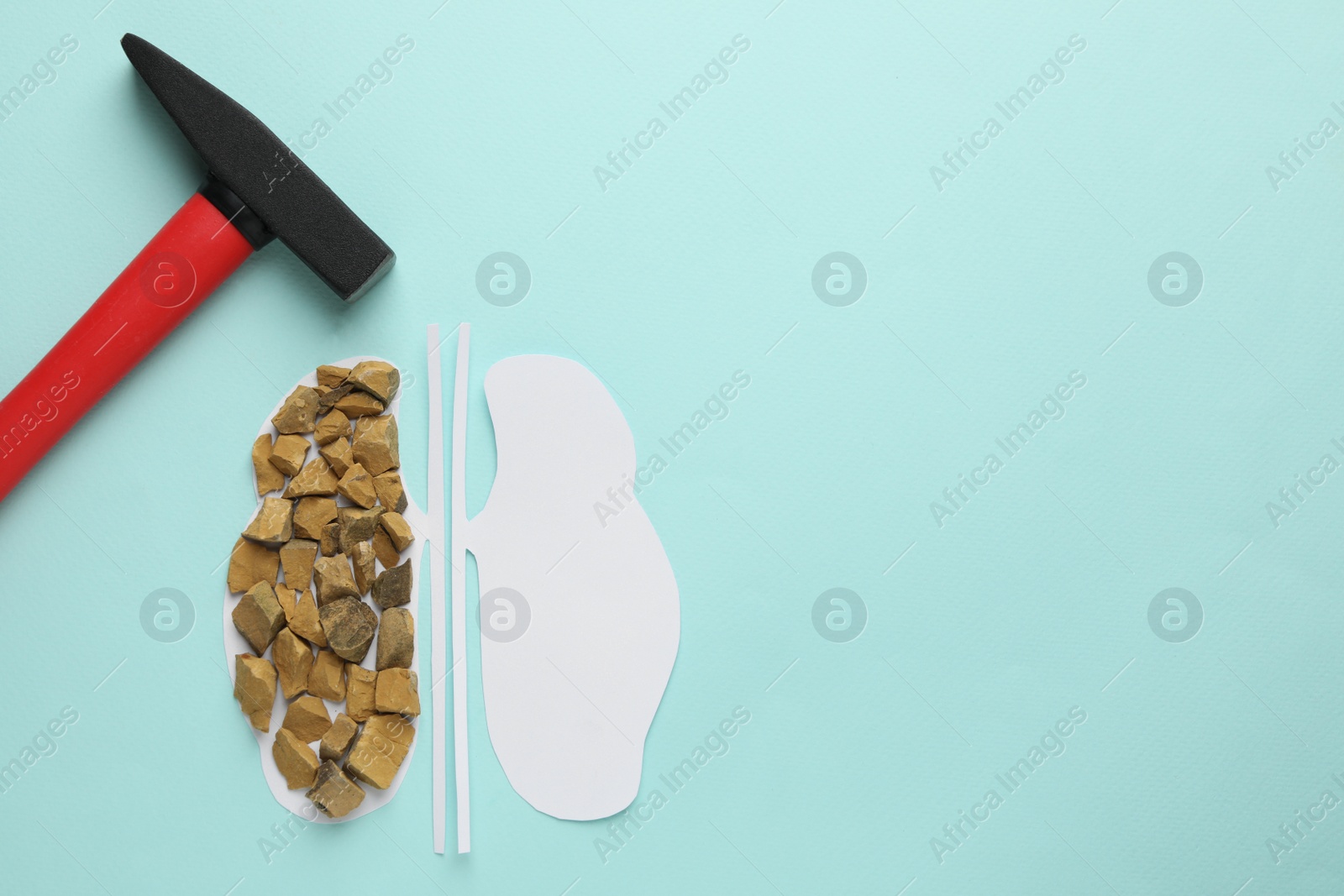 Photo of Paper cutout of kidneys with stones and hammer on turquoise background, flat lay. Space for text