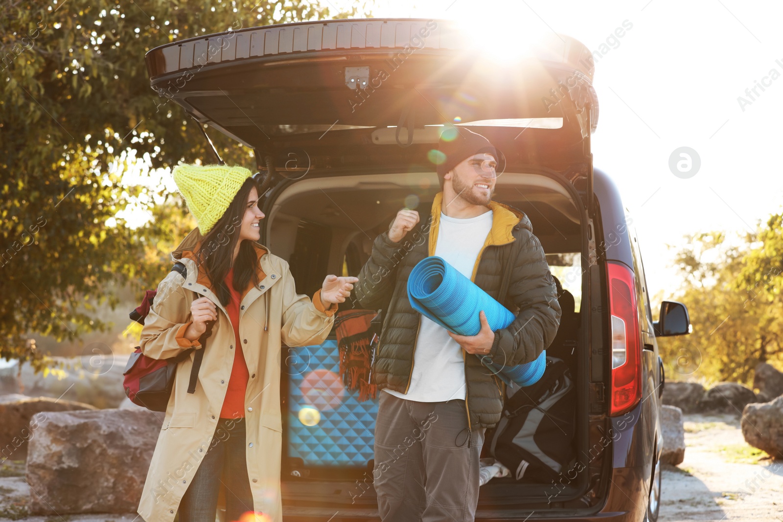 Photo of Young couple with camping equipment near car trunk outdoors