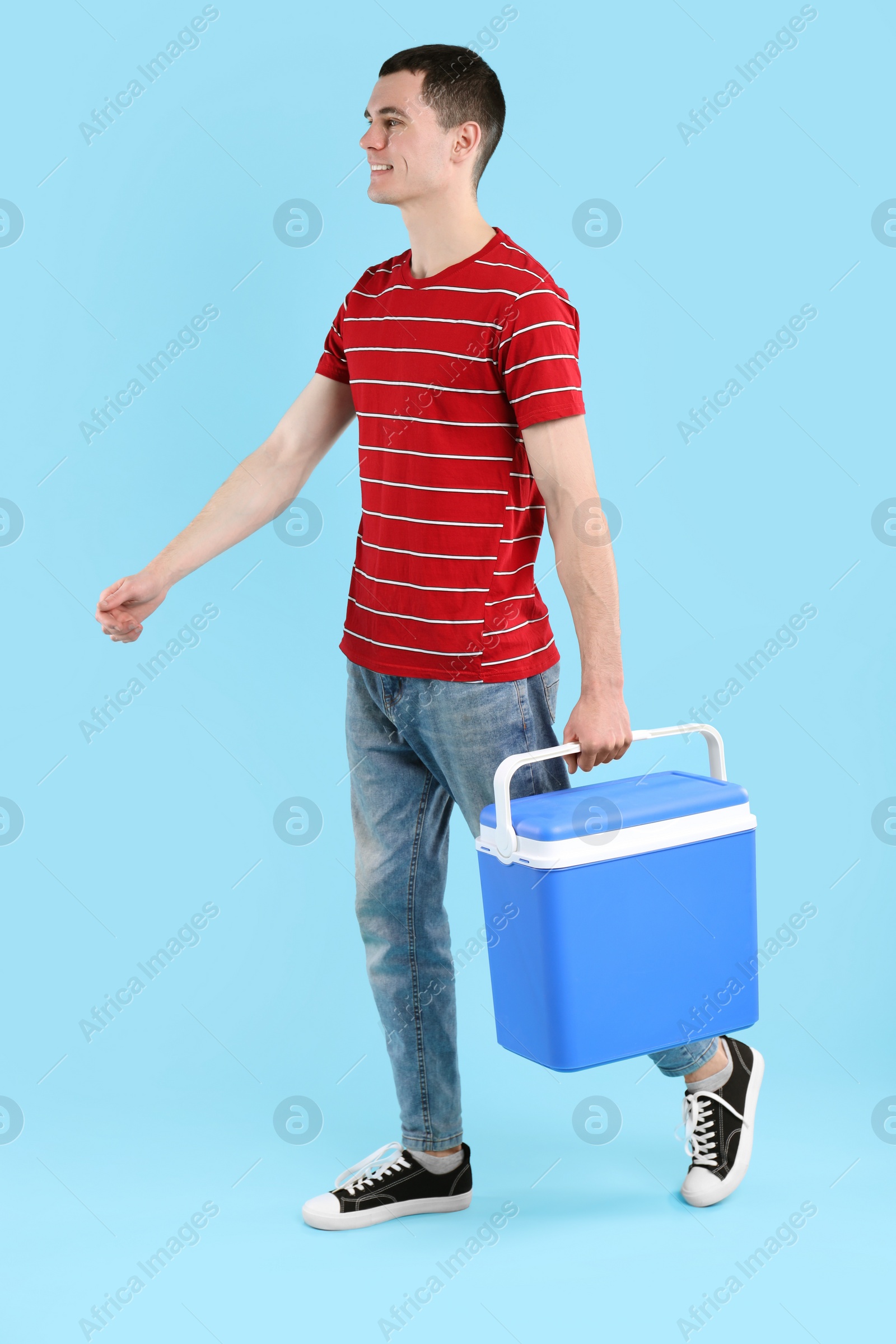 Photo of Man with cool box walking on light blue background