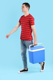 Photo of Man with cool box walking on light blue background