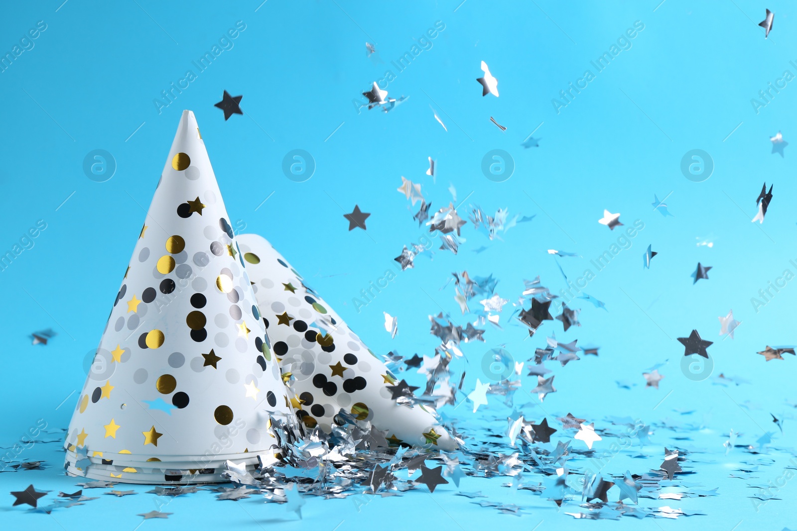 Photo of Party hats and confetti on light blue background