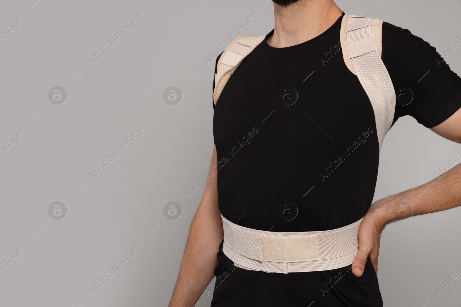Photo of Closeup view of man with orthopedic corset on grey background, space for text