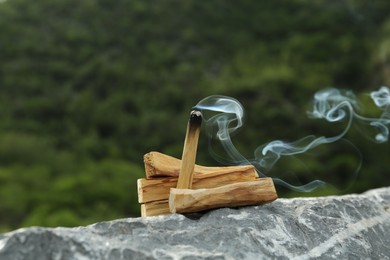 Burning palo santo stick on stone surface outdoors