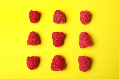 Flat lay composition with delicious ripe raspberries on yellow background