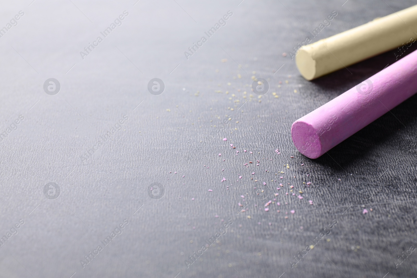 Photo of Pieces of color chalk on blackboard, space for text