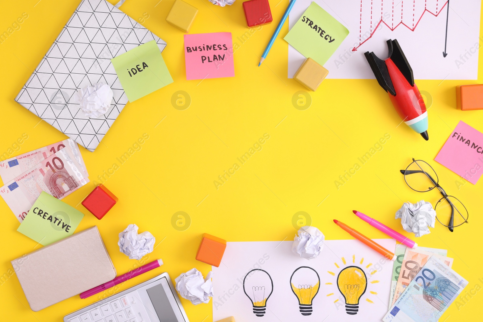 Photo of Frame of stationery, money and toy rocket on yellow background, flat lay with space for text. Startup concept