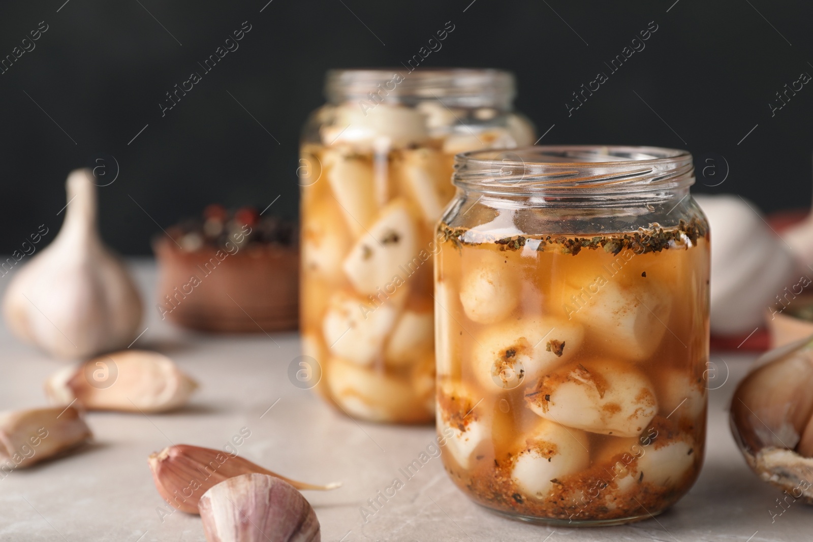 Photo of Preserved garlic in glass jar on table, closeup. Space for text