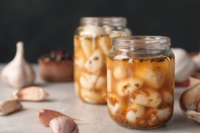 Photo of Preserved garlic in glass jar on table, closeup. Space for text