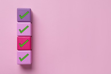 Cubes with check marks on pink background, top view. Space for text