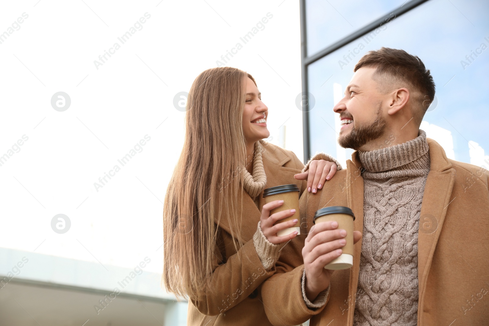 Photo of Lovely couple with cups of coffee on city street in morning