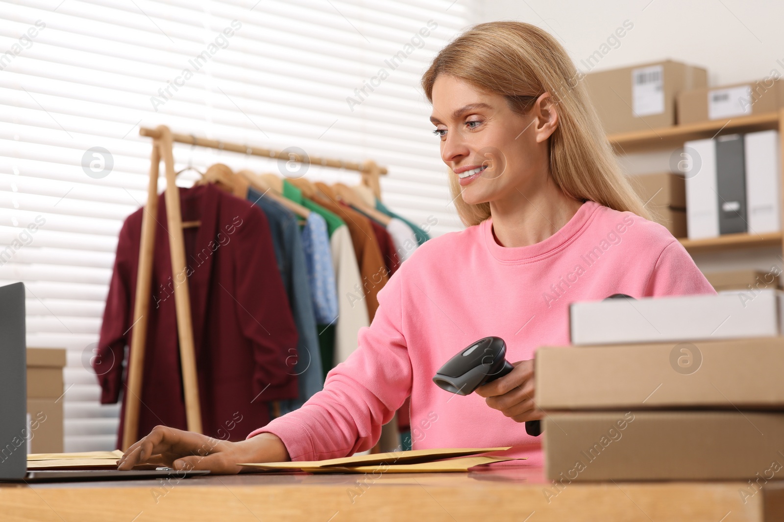 Photo of Seller with scanner reading parcel barcode in office. Online store