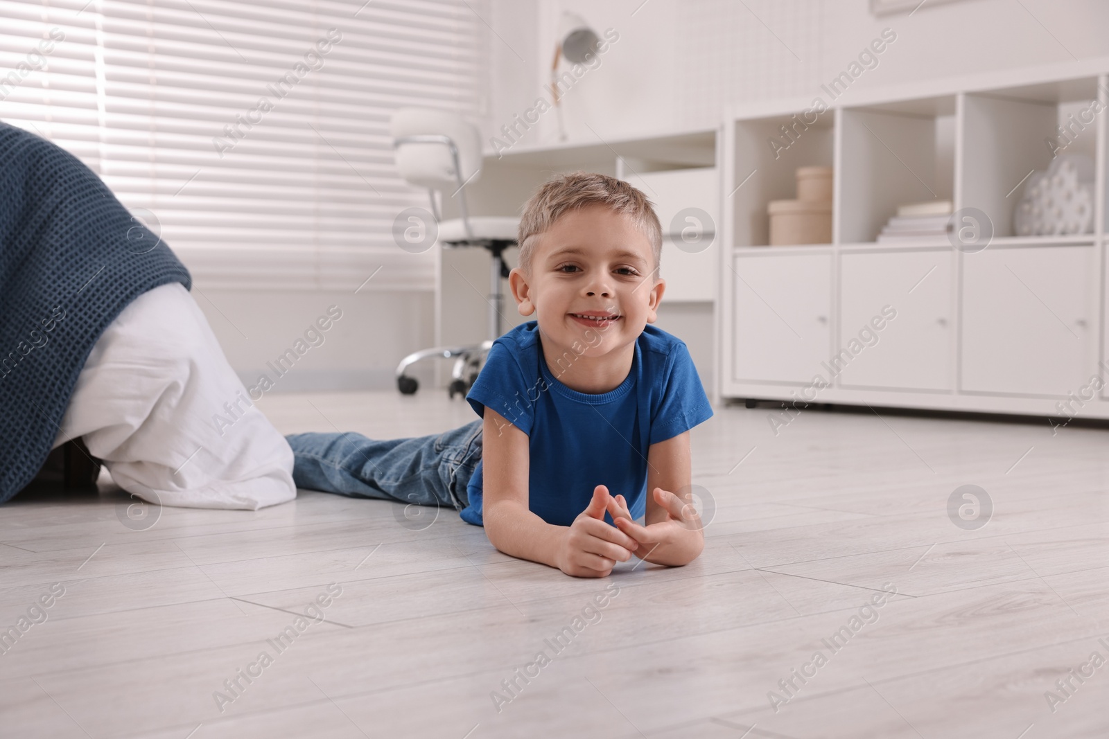 Photo of Cute little boy lying on warm floor at home. Heating system