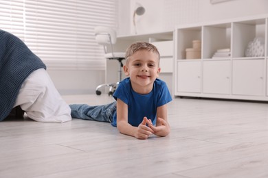 Cute little boy lying on warm floor at home. Heating system