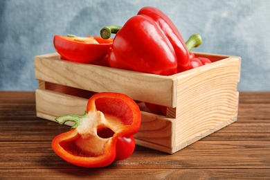 Photo of Crate with ripe paprika peppers on wooden table