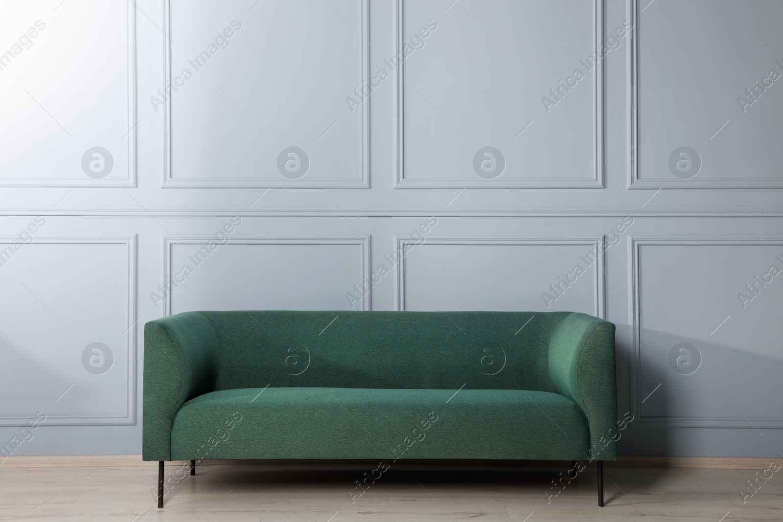 Photo of Comfortable sofa near stylish white wall indoors