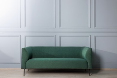 Comfortable sofa near stylish white wall indoors
