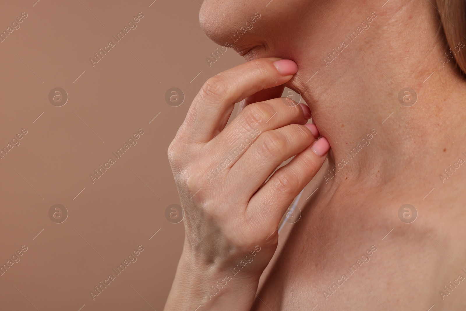 Photo of Mature woman touching her neck on beige background, closeup. Space for text