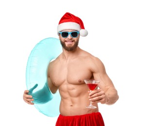 Photo of Muscular young man in Santa hat with inflatable ring and cocktail on white background