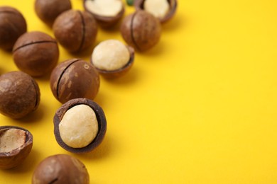 Photo of Tasty Macadamia nuts on yellow background, closeup. Space for text