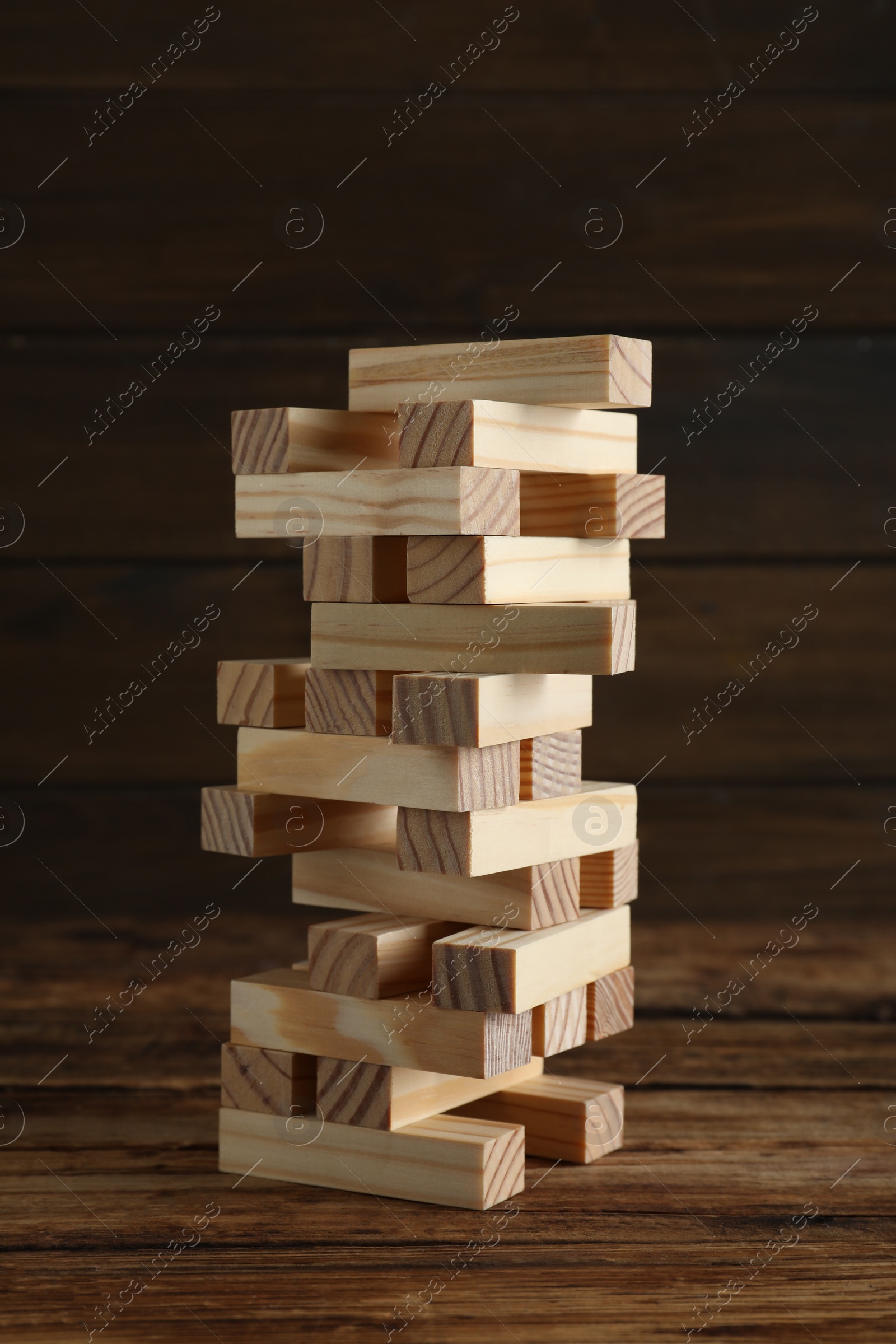 Photo of Jenga tower made of wooden blocks on table