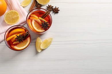 Photo of Aromatic punch drink and ingredients on white wooden table, flat lay. Space for text