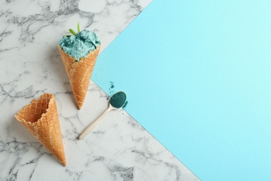 Photo of Flat lay composition with delicious spirulina ice cream cones and powder on marble table. Space for text