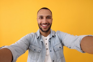 Photo of Smiling young man taking selfie on yellow background