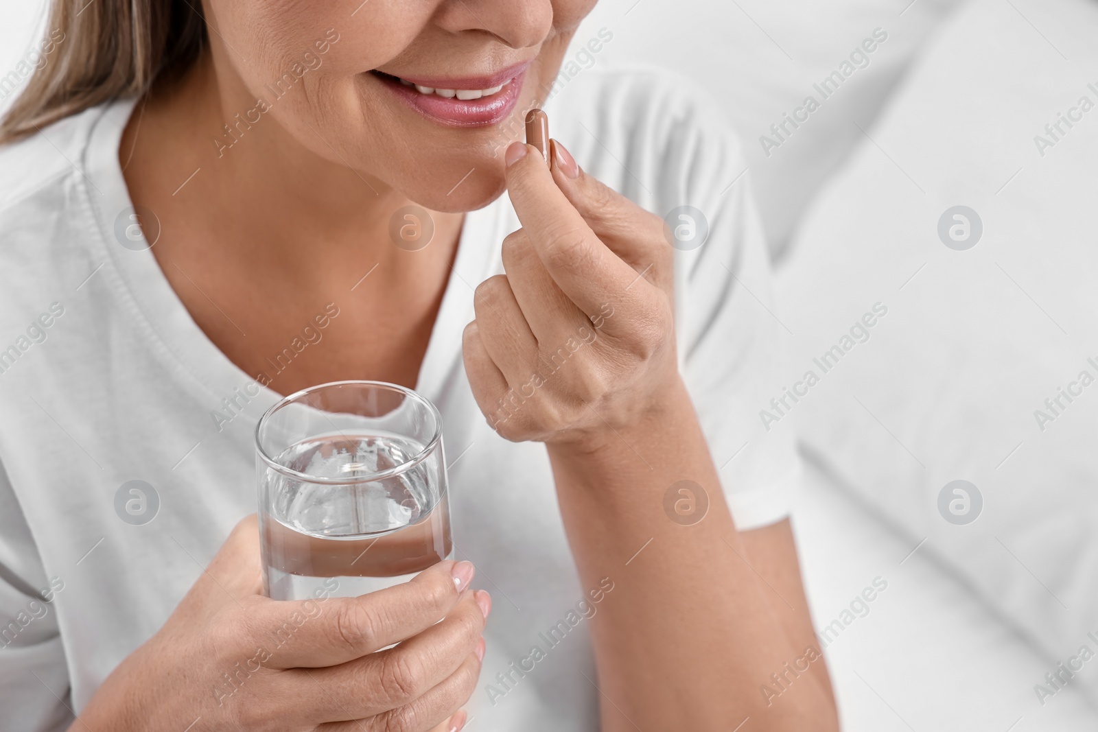 Photo of Woman taking vitamin pill at home, closeup