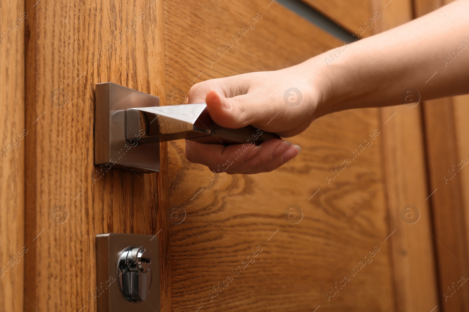 Photo of Woman opening wooden door indoors, closeup view