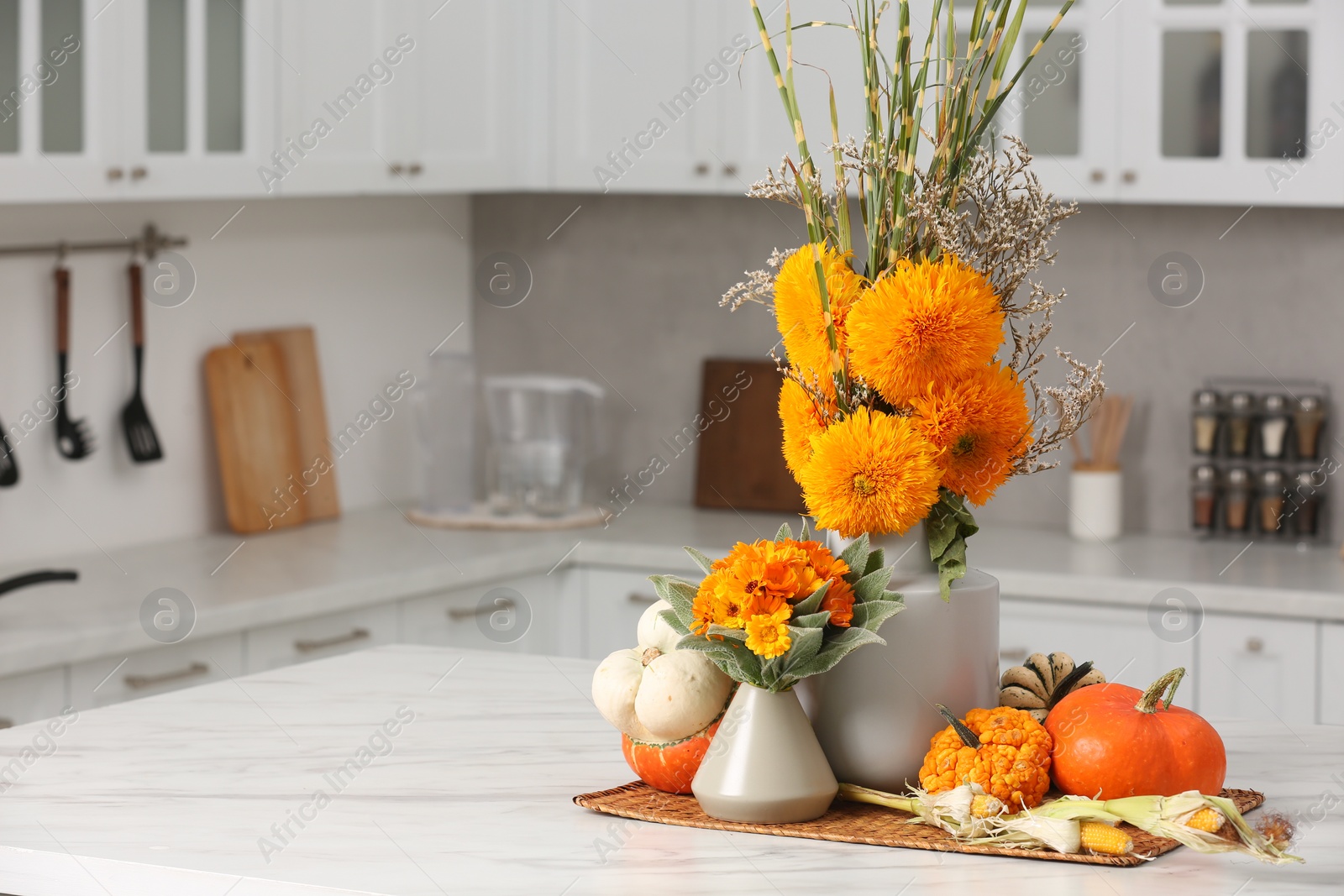 Photo of Beautiful autumn bouquets and pumpkins on marble table in kitchen