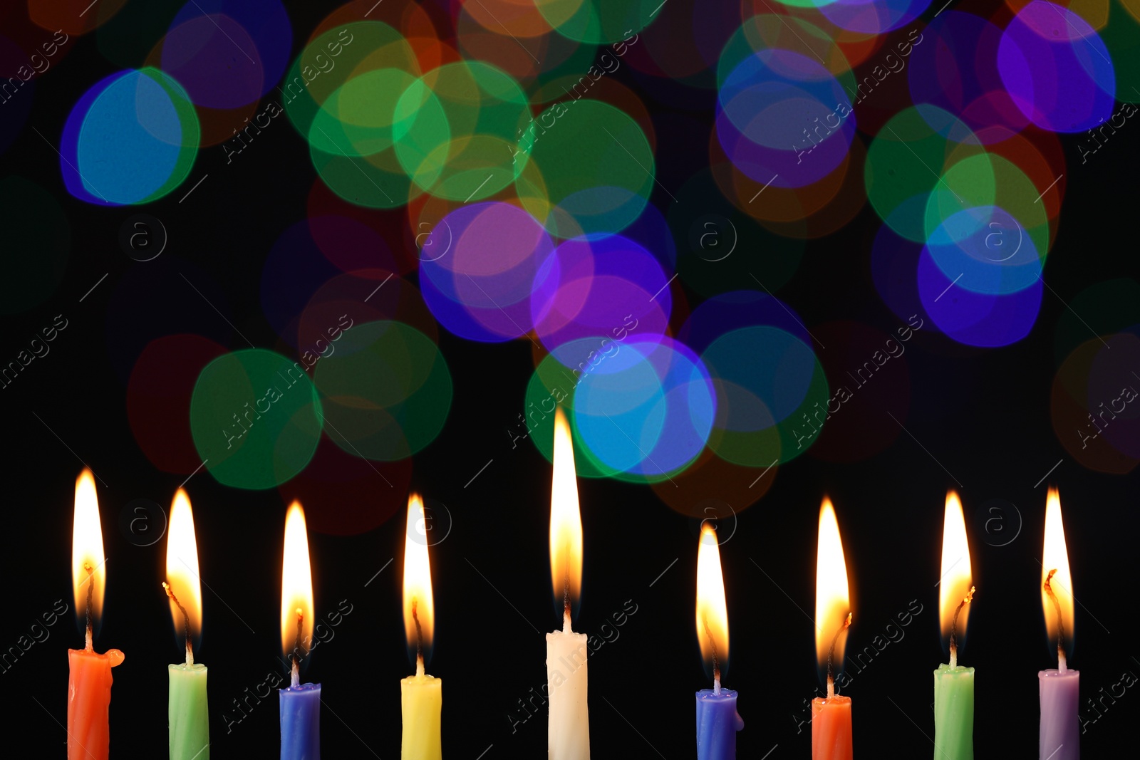 Photo of Hanukkah celebration. Burning candles against blurred lights, closeup