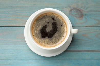 Photo of Cup of aromatic coffee on light blue wooden table, top view