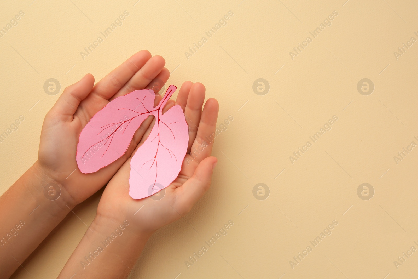 Photo of Child holding paper human lungs on beige background, top view. Space for text