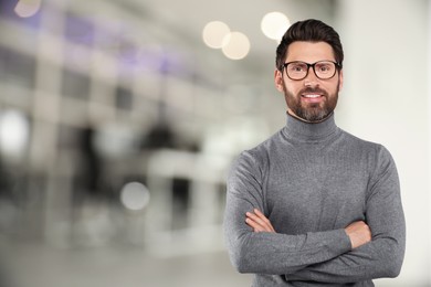 Handsome confident man with eyeglasses in office, space for text
