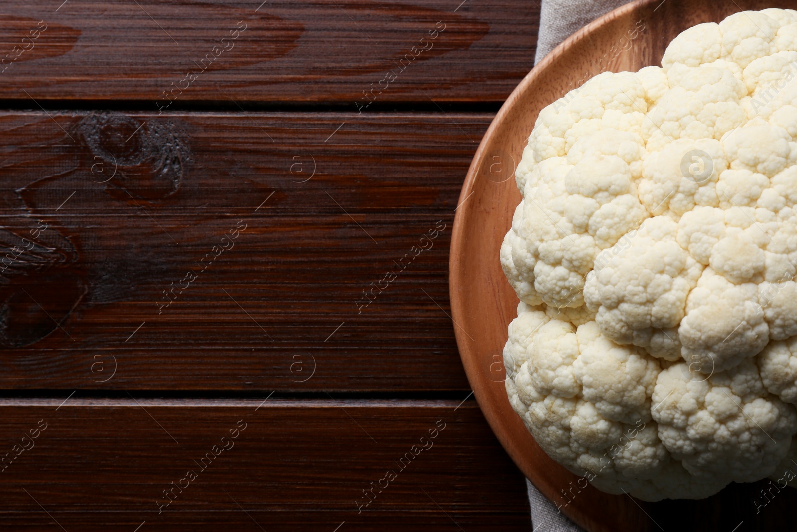 Photo of Plate with fresh raw cauliflower on wooden table, top view. Space for text