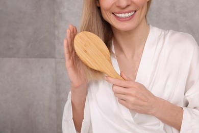 Woman in white robe brushing her hair indoors, closeup