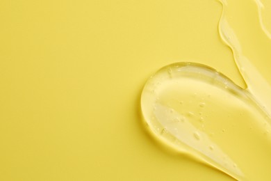 Photo of Sample of clear cosmetic gel on yellow background, top view. Space for text