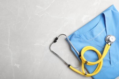 Photo of Top view of stethoscope and medical uniform on light background. Space for text