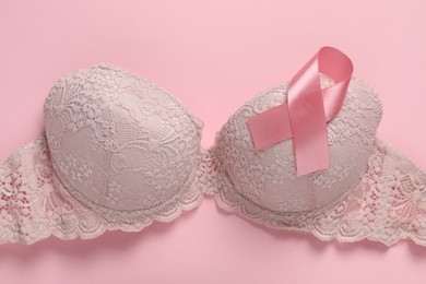 Photo of Pink ribbon and bra on color background, top view. Breast cancer awareness