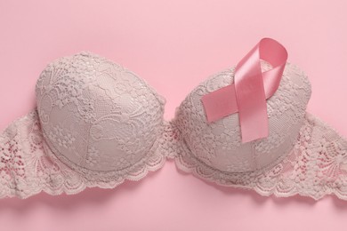 Pink ribbon and bra on color background, top view. Breast cancer awareness