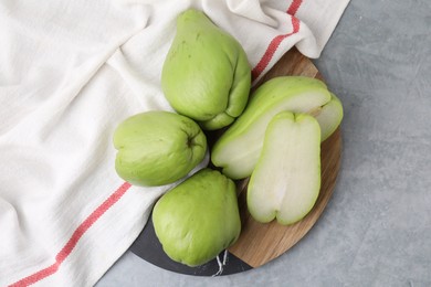 Photo of Cut and whole chayote on gray table, top view