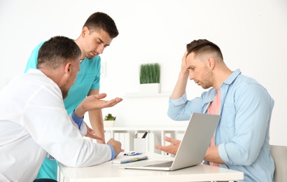 Male doctor and his assistant working with patient in clinic. Cardiology consultation