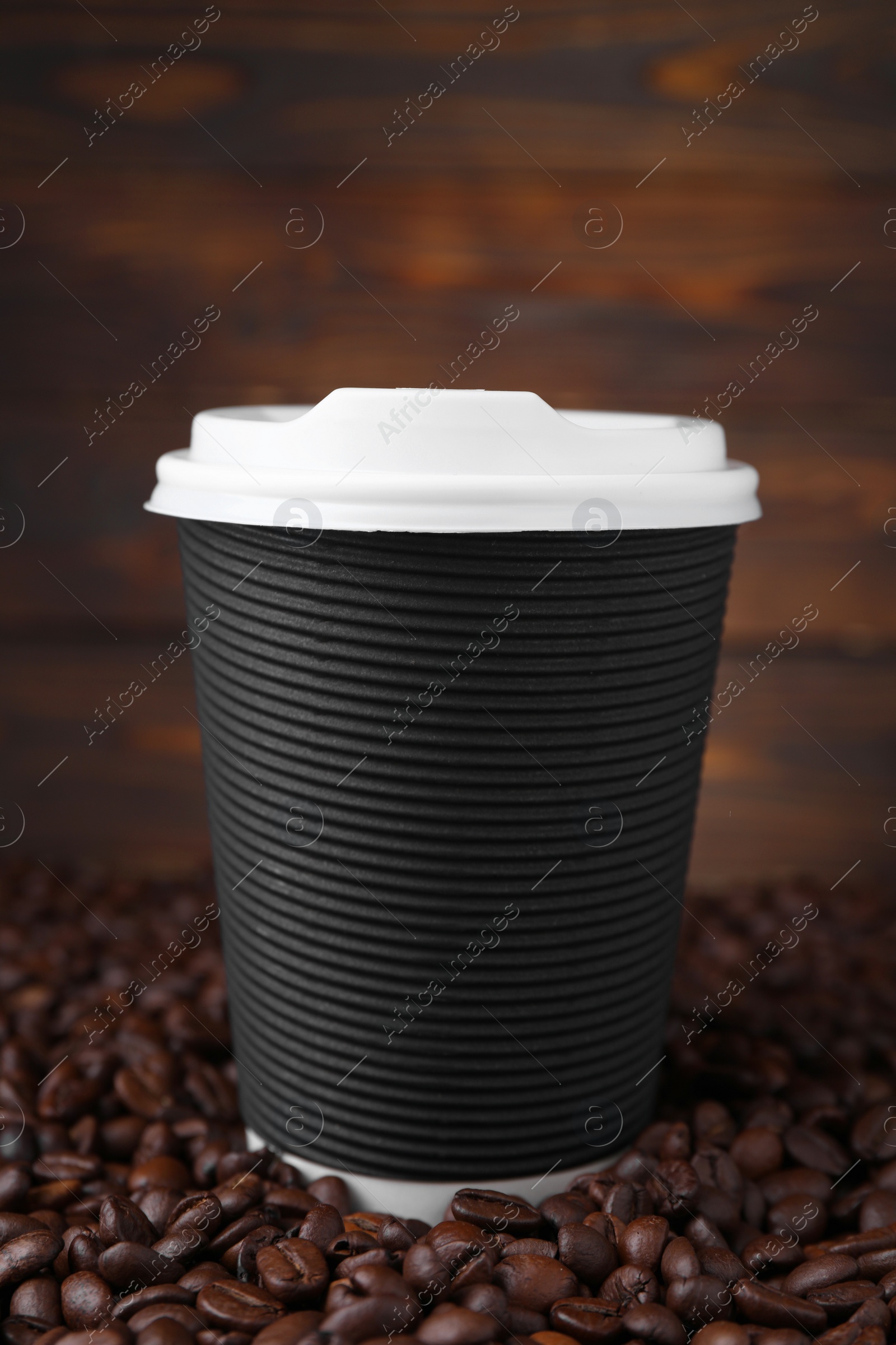 Photo of Coffee to go. Paper cup and roasted beans against wooden background