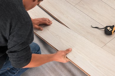 Photo of Professional worker installing new laminate flooring, closeup