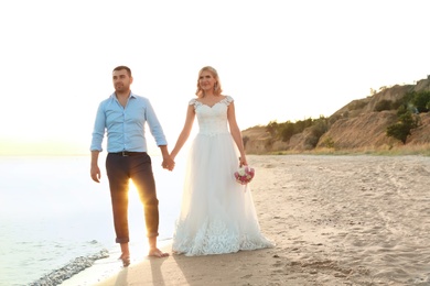 Wedding couple holding hands together on beach. Space for text