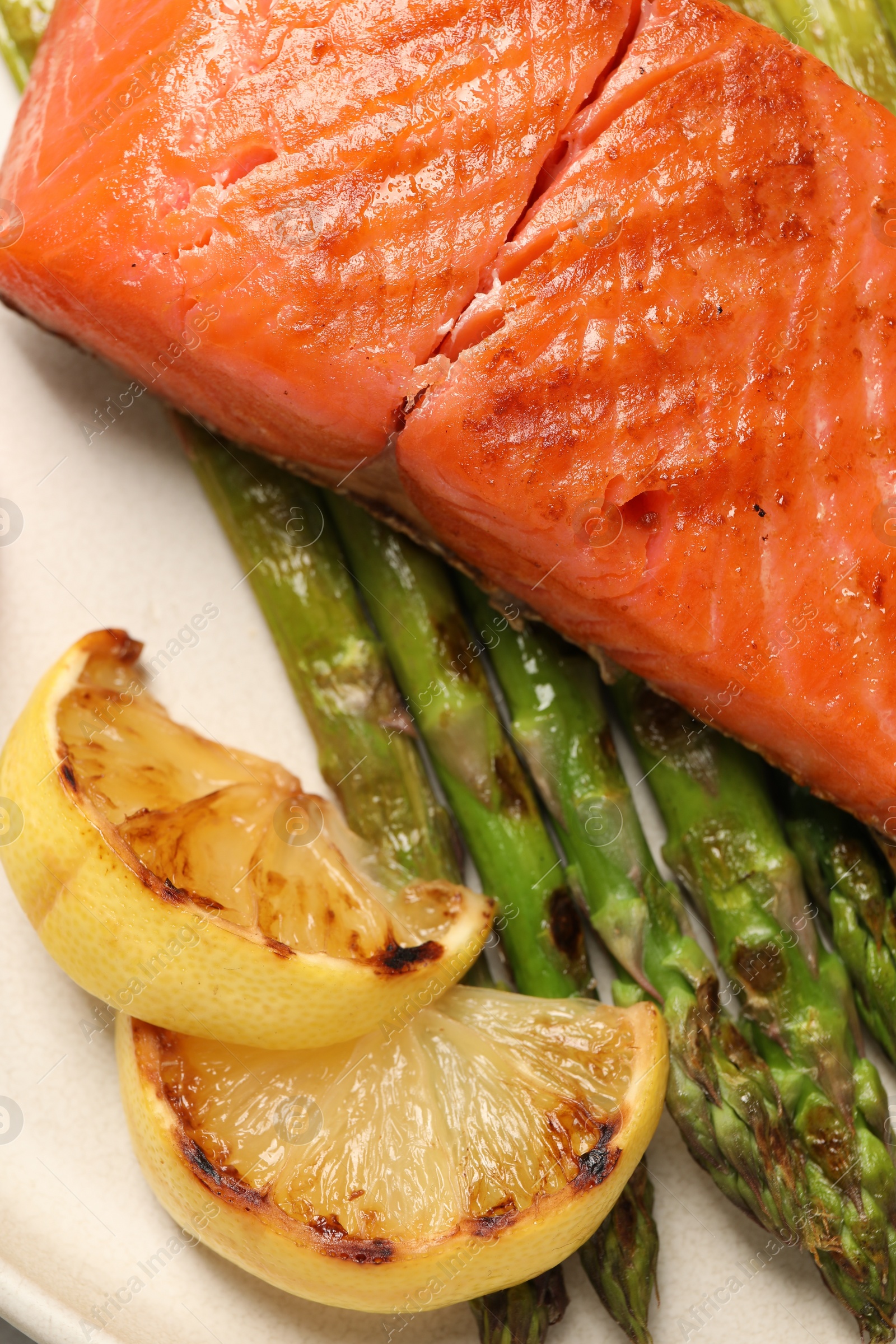 Photo of Tasty grilled salmon with asparagus, tomatoes and lemon on plate, flat lay