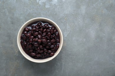 Photo of Bowl of canned kidney beans on grey table, top view. Space for text